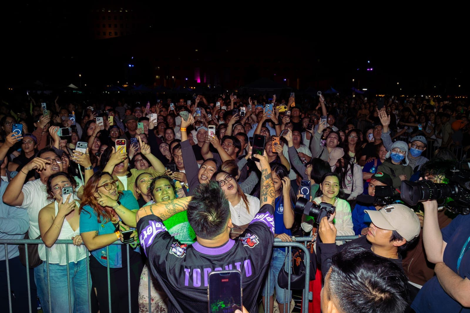 AJ Rafael leans over the barricade in a Raptors jersey to hug fans at Philippine Festival Mississauga, a wall of raised phones behind them