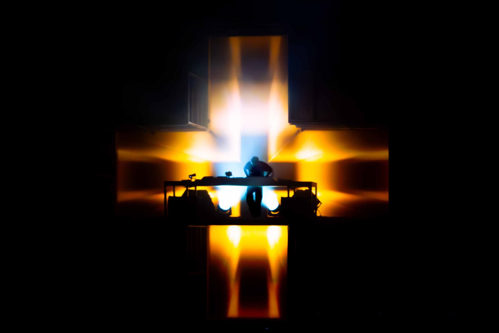 Artist silhouette in front of a huge crowd with beams of light cutting through fog